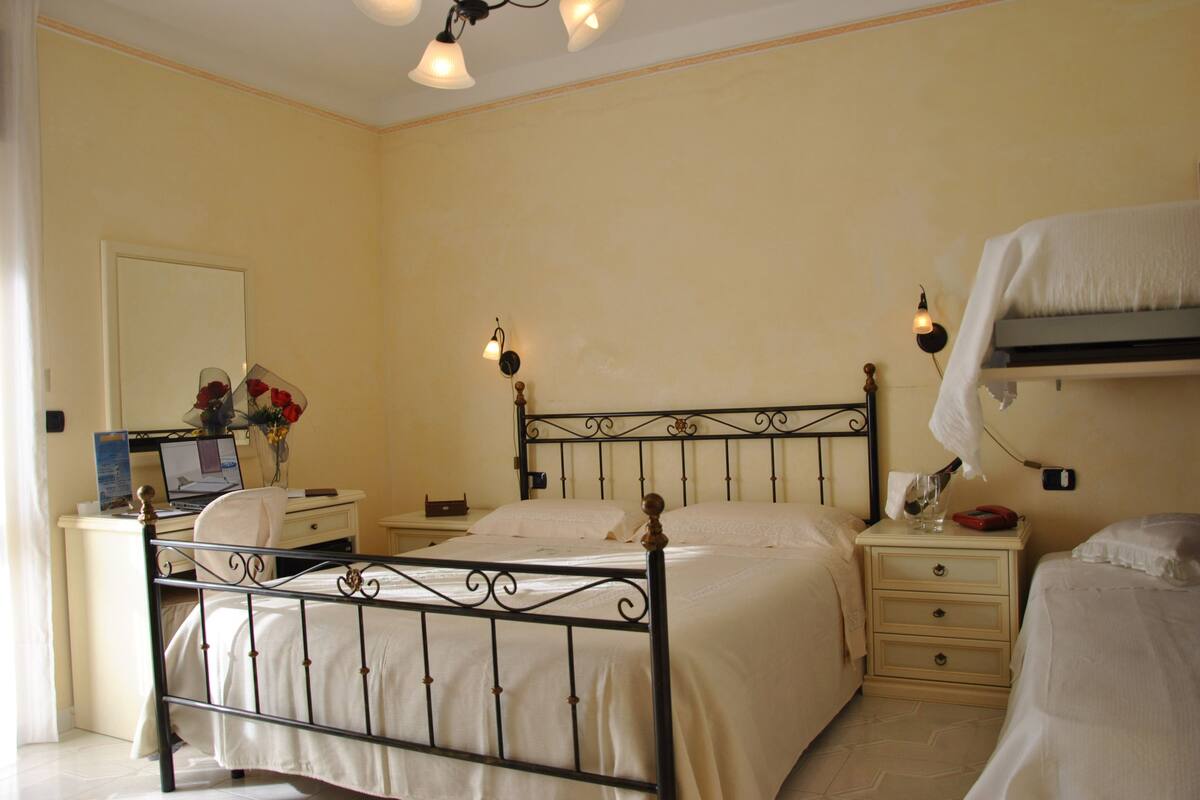 Une chambre à coucher avec un lit, des tables de chevet, un bureau et un miroir.