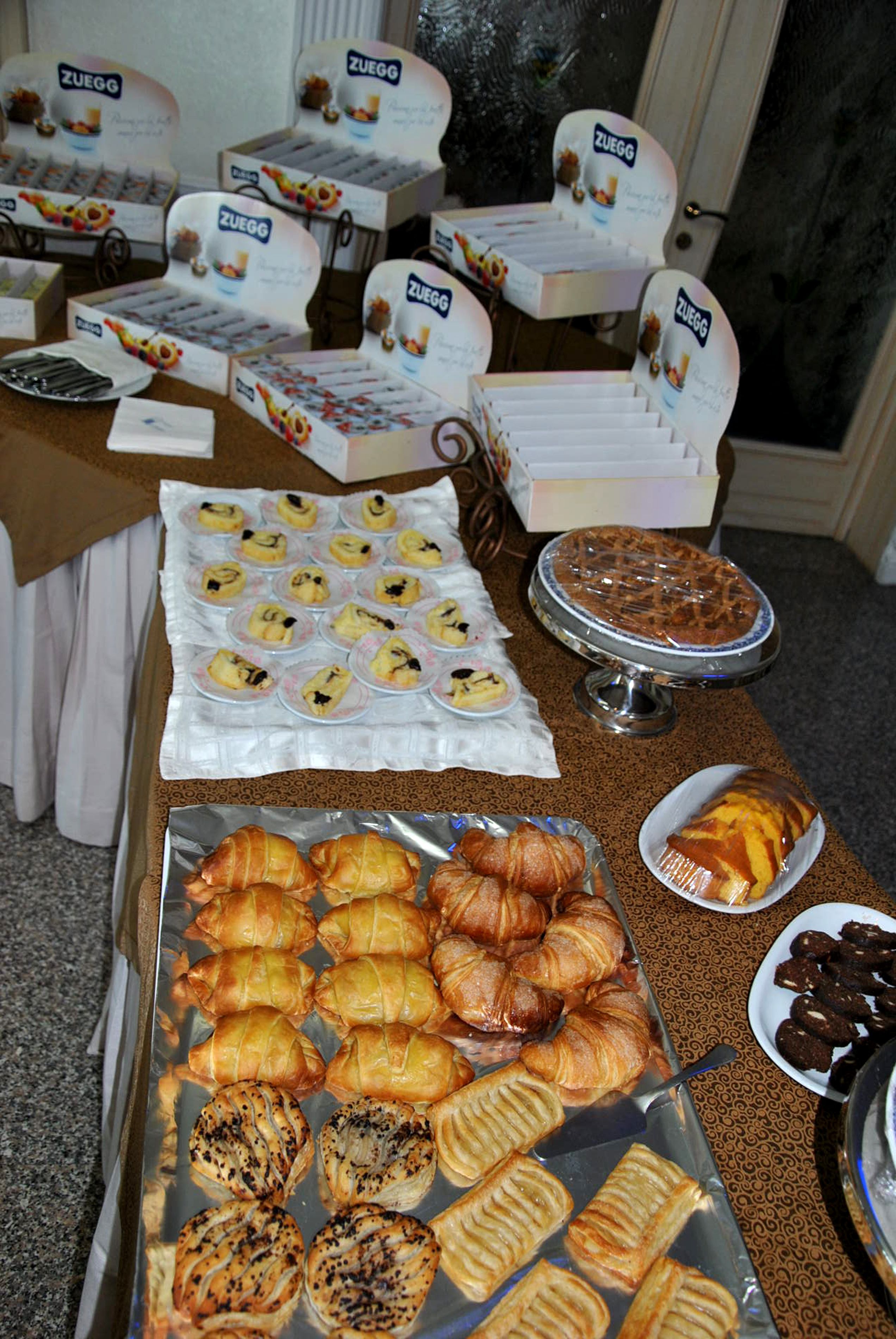 Ein reichhaltiges Buffet mit verschiedenen Backwaren, darunter Gebäck, Muffins und eine Torte.