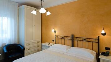 A hotel room with a bed, a wardrobe, a chair, and two bedside lamps.