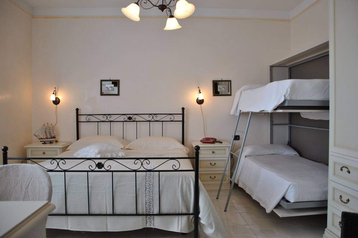 Une chambre à coucher comprenant un lit, des tables de chevet, une commode, une chaise et un lit superposé.