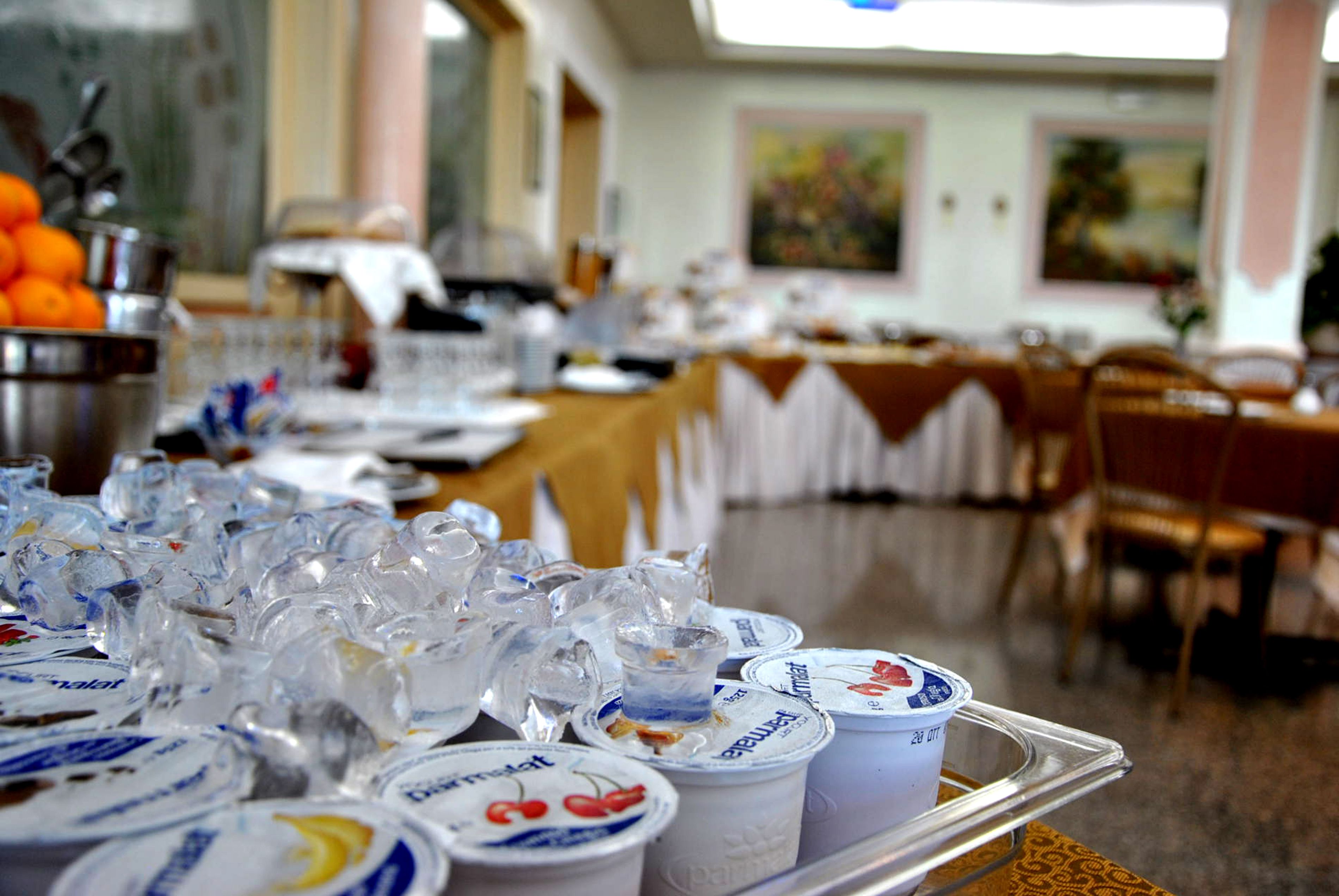 Una mesa de buffet con diversos alimentos y una bandeja de vasos de yogur.