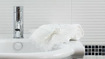 A white bathroom sink with a chrome faucet and a lace towel.