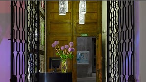 A wooden door with a sign reading "SALIDA" and a glass vase with purple flowers on a desk. - Marquis Hotels Portago (Granada)