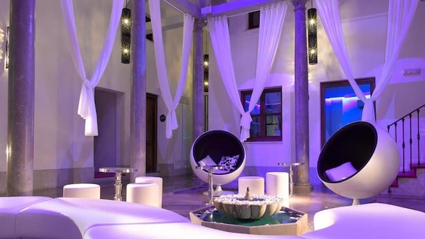 A luxurious interior with a curved seating area, elegant arches, and ambient lighting. - Marquis Hotels Portago (Granada)