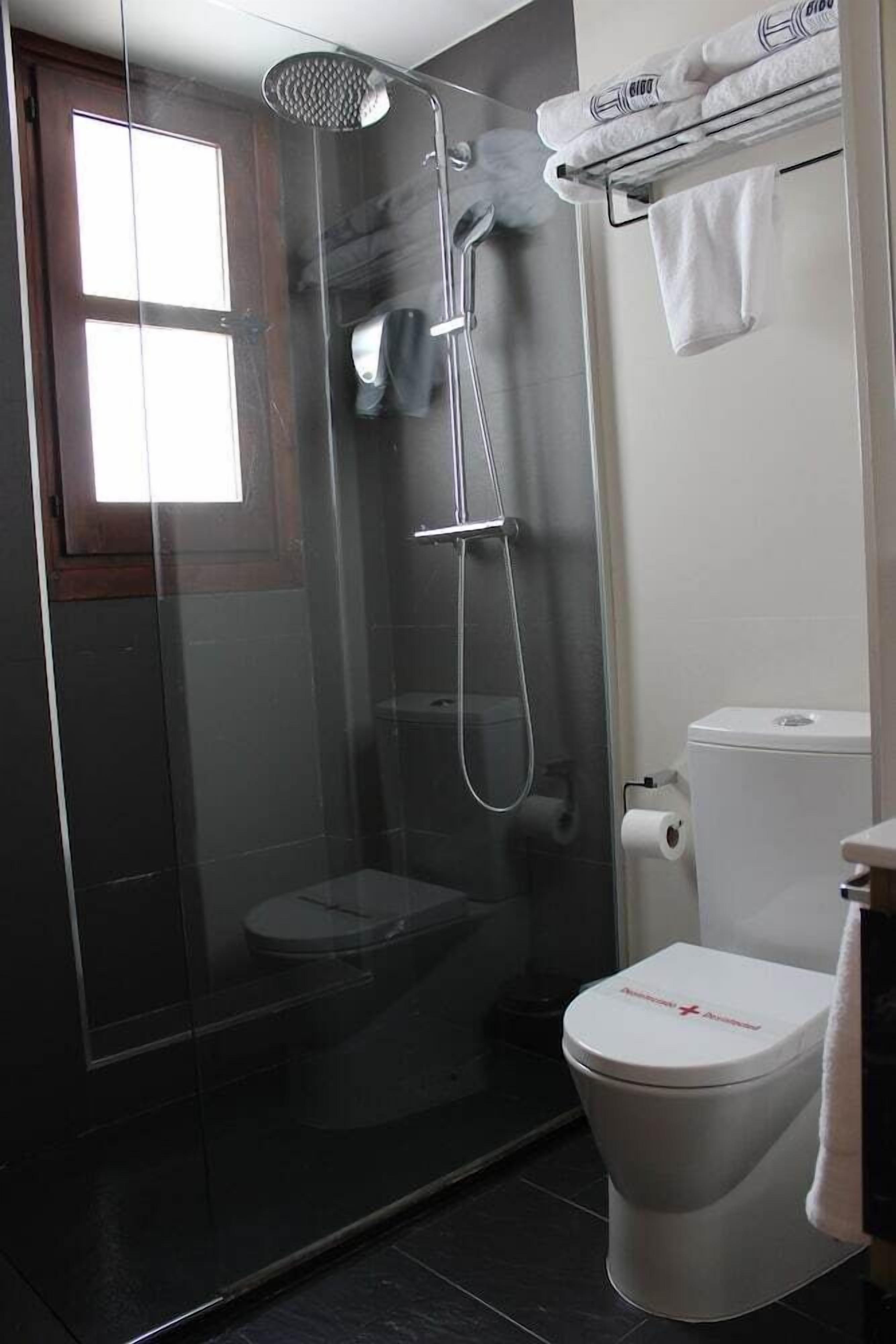 Une salle de bain moderne avec une douche à parois de verre, des toilettes et un porte-serviettes avec des serviettes pliées.