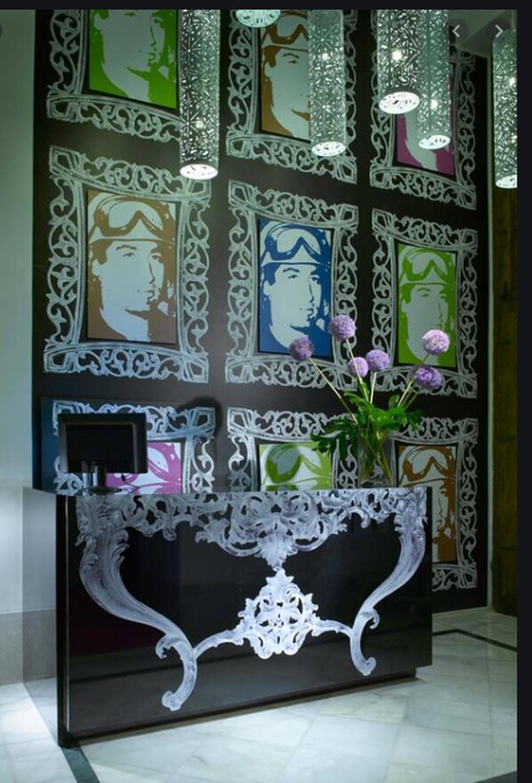 A reception desk with a black and white ornate design, surrounded by framed artwork on the wall.