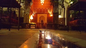 A courtyard with a fountain, a seating area, and a building with ornate architecture. - Riad Jenaï Demeures du Maroc (Marrakech)