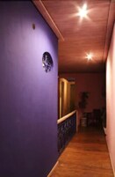 Un pasillo estrecho con suelo de madera y una pared morada.
