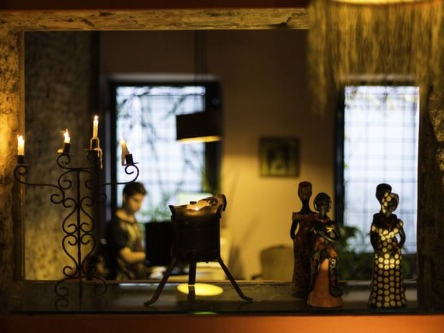 A cozy room with a rustic stone wall, a small table with candles, and a window with a view of the outside.