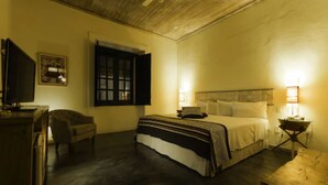 Una habitación de hotel con cama, lámparas de noche, escritorio y televisión.