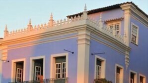 Un edificio de dos pisos con balcones, ventanas grandes y vista a la calle.