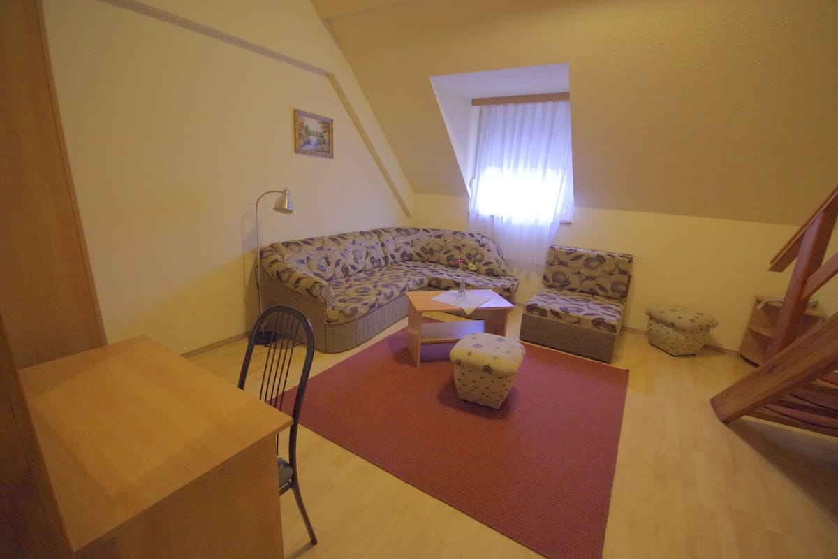 Una habitación acogedora con sofá, una mesita, una silla y un escritorio de madera.