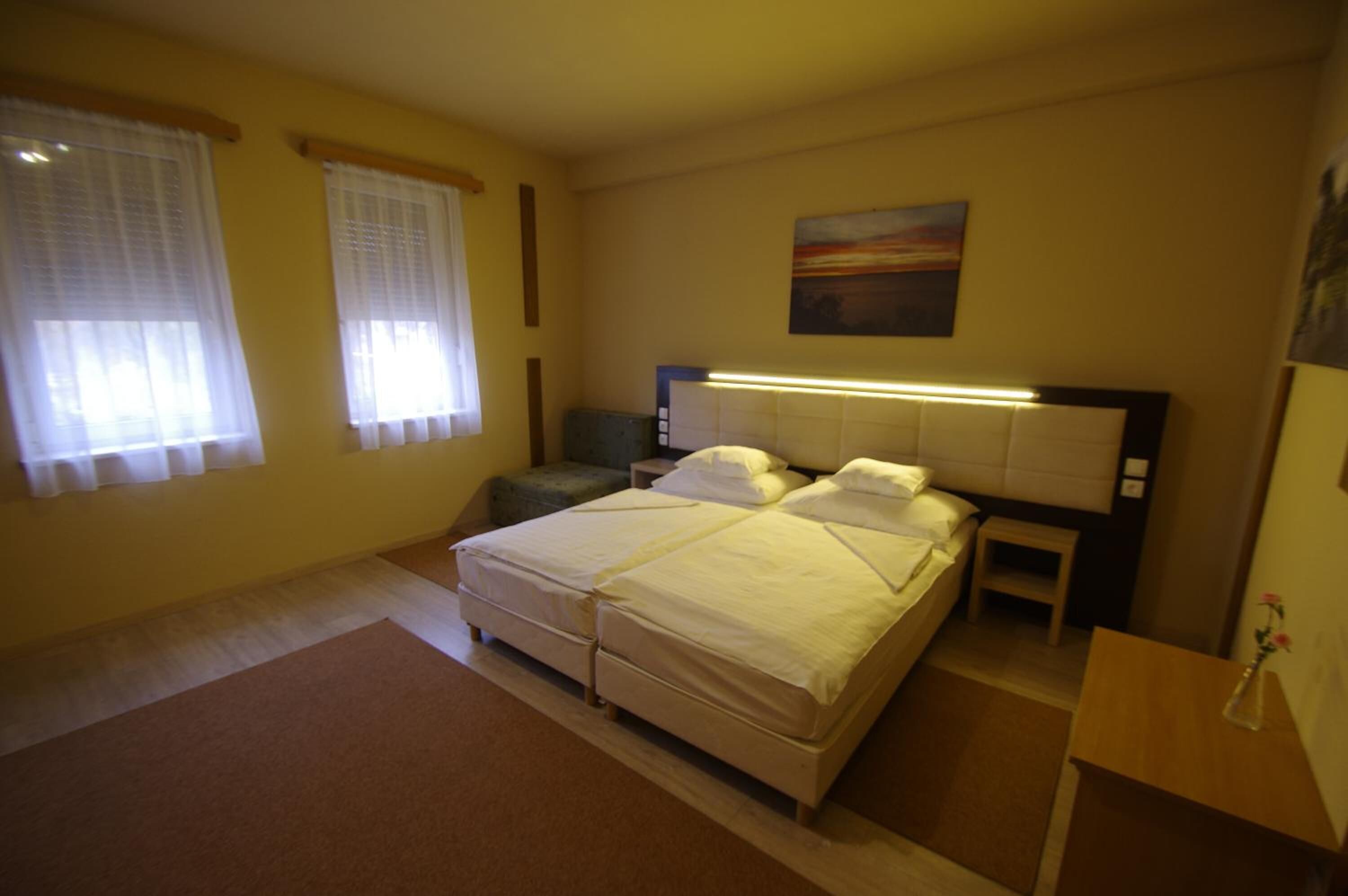 Ein Schlafzimmer mit zwei Einzelbetten, einem Nachttisch, einem Beistelltisch und einem Bild an der Wand.