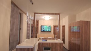 A modern bathroom with a vanity, a large mirror, a television, and wooden cabinetry. - Hotel Vadászkürt Superior (Szekesfehervar)