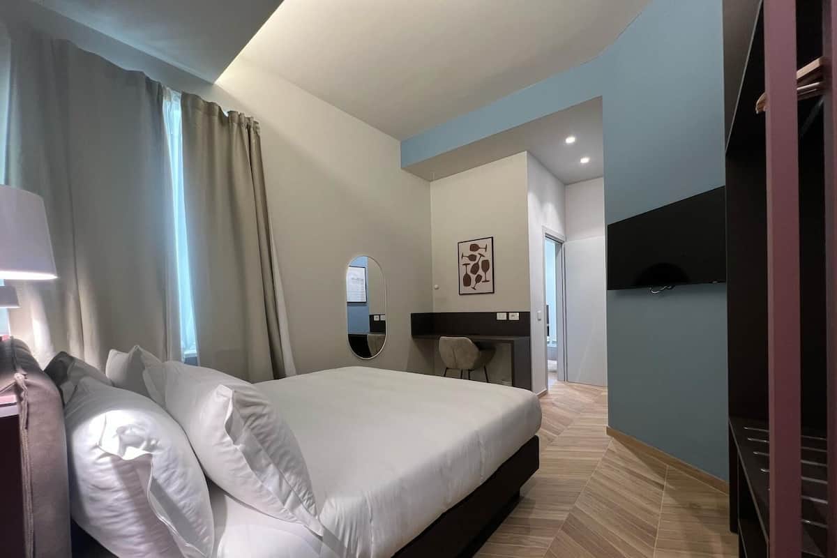Una habitación de hotel moderna con una cama grande, un escritorio y un espejo.