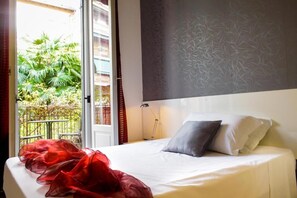 A hotel room with a bed, a nightstand, and a window with a view of greenery outside. - Hotel RossoVino (Milan)