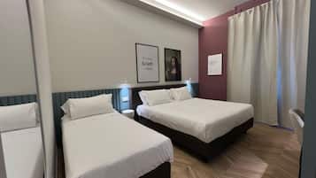 Une chambre d’hôtel avec deux lits, un miroir, un tableau encadré représentant une femme et une lampe fixée au mur.