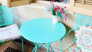 An open balcony with a bed, a table, and chairs. - Eden Hotel (Haifa)