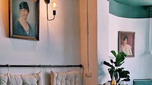 A dining area with a high table and chairs, cushioned seating, and wall-mounted light fixtures. - Eden Hotel (Haifa)