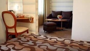 Una habitación de hotel con cama, escritorio, silla, sofá y una mesita con un florero.