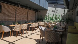 Un restaurante moderno con paredes de ladrillo, mesas de madera y sillas acolchadas.