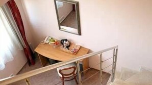 Una escalera que lleva a una habitación con un escritorio de madera, una silla y un espejo en la pared.