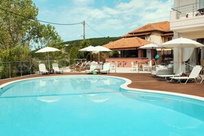 Una piscina al aire libre, sombrillas, sillones reclinables de piscina