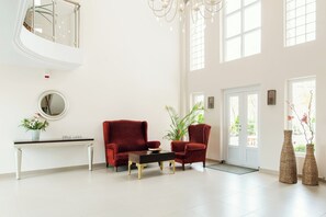 Un vestíbulo amplio con un sofá rojo, un espejo redondo y una consola con una planta en maceta.