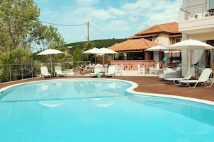 Una piscina al aire libre, sombrillas, sillones reclinables de piscina