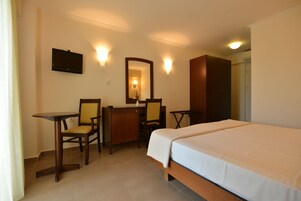 A hotel room with a bed, a desk, two chairs, a TV, and a mirror.