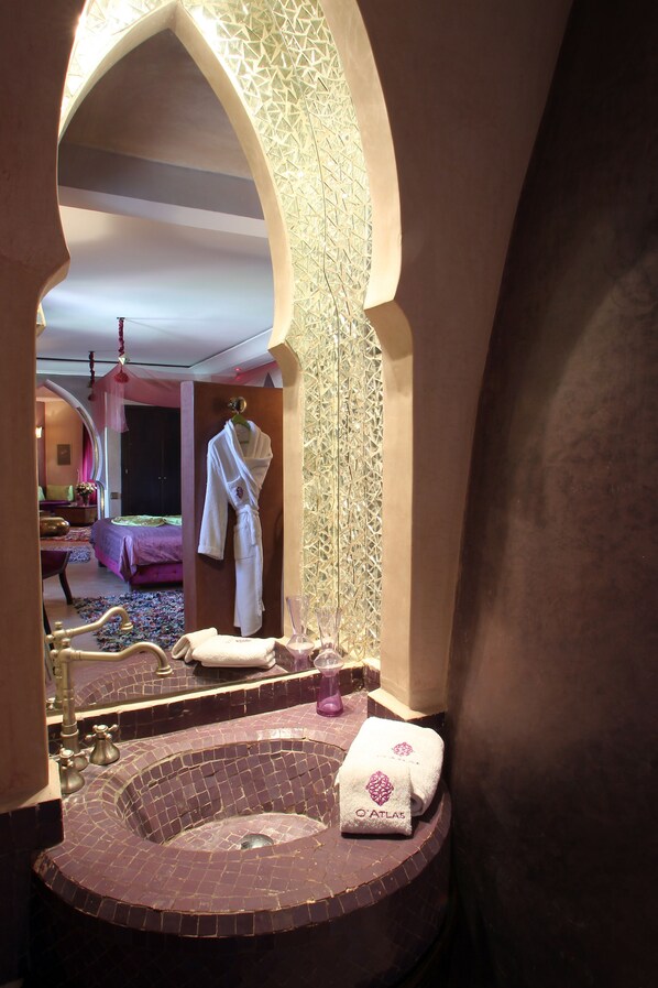 A bathroom with a freestanding bathtub, a robe hanging on a hook, and a towel on the edge of the tub.
