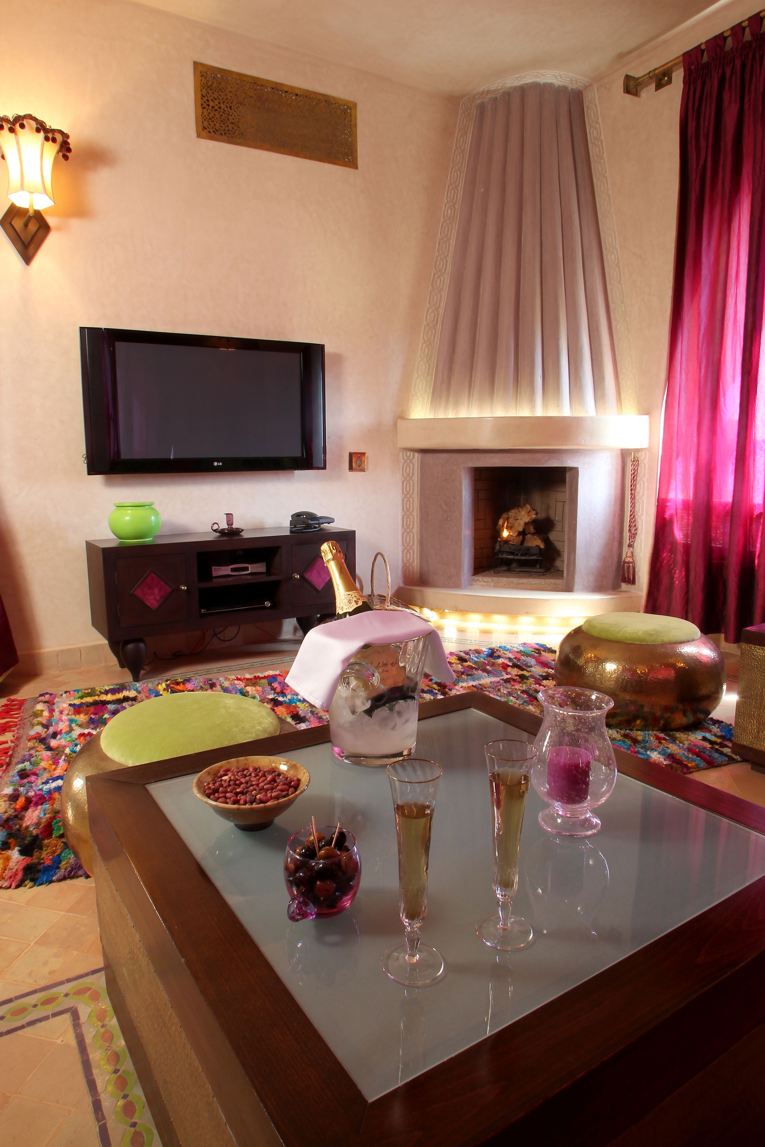 A living room with a fireplace, a television mounted on the wall, and a coffee table with various items.