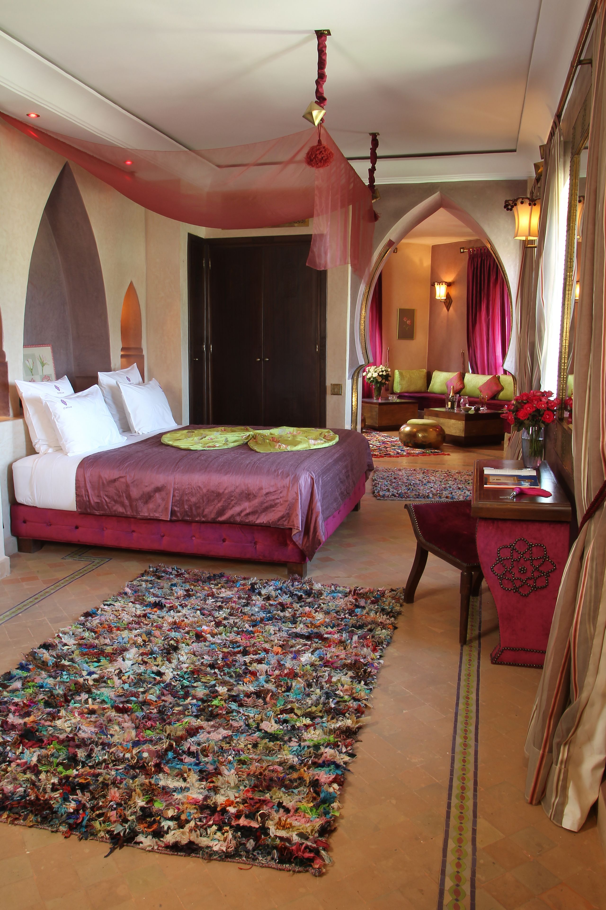 Un dormitorio con una cama grande, un tapete colorido y un espejo con marco decorativo.