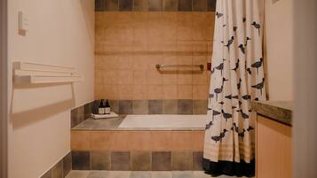 Un baño con bañera, toallero y cortina de ducha con estampado de aves.
