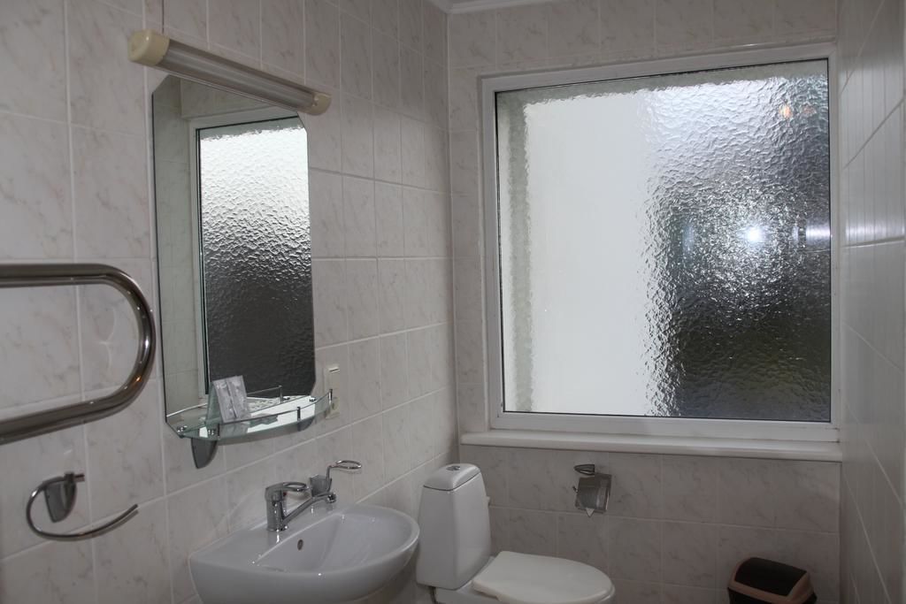 Et badeværelse med vask, toilet og et vindue.