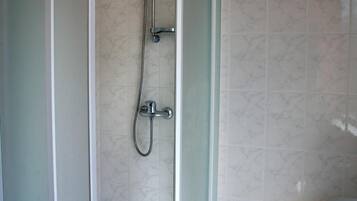 Un baño moderno con cabina de ducha acristalada, inodoro y cubo de basura.