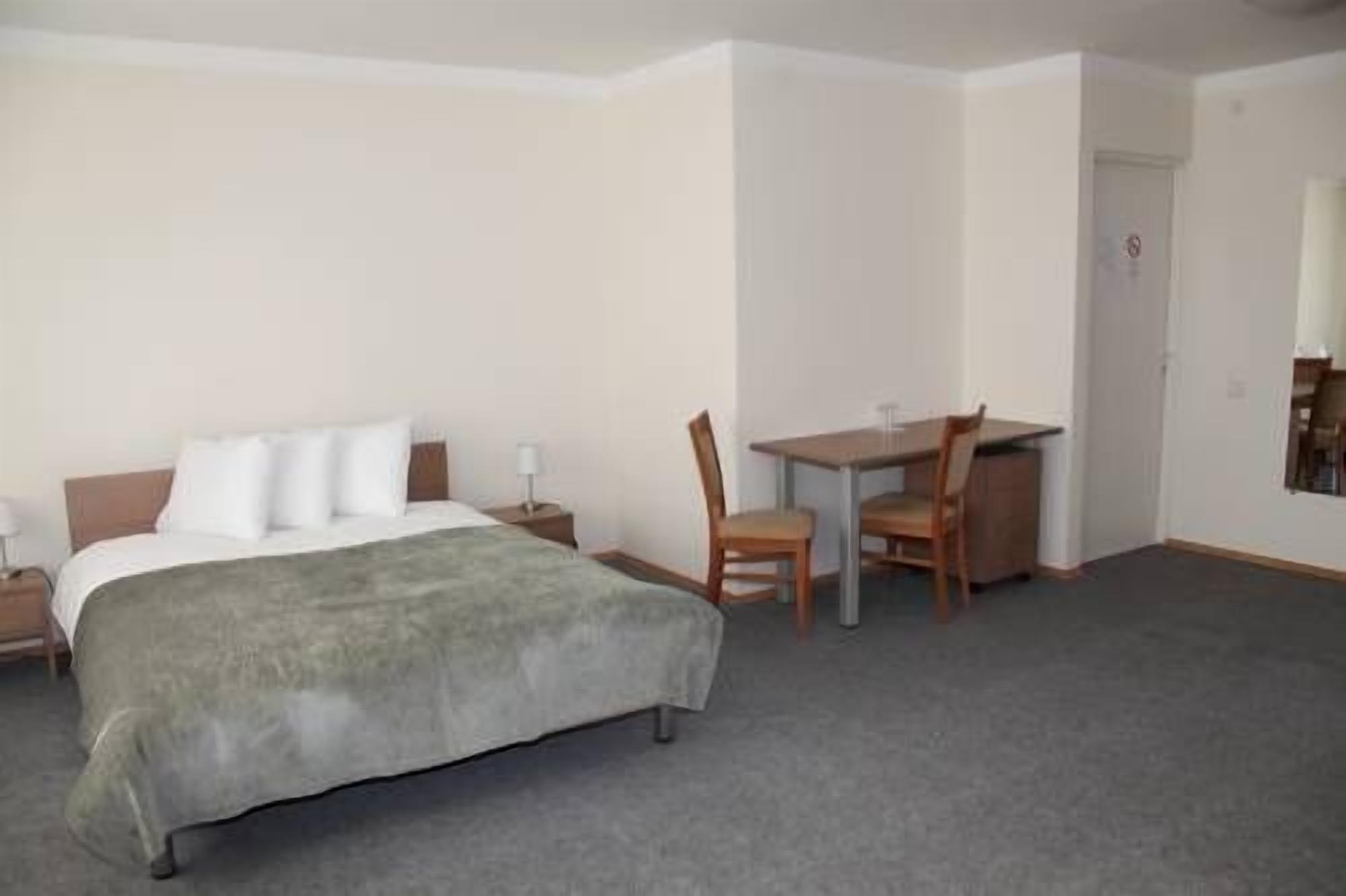 Hotellihuone, jossa on sänky, työpöytä ja tuoli.