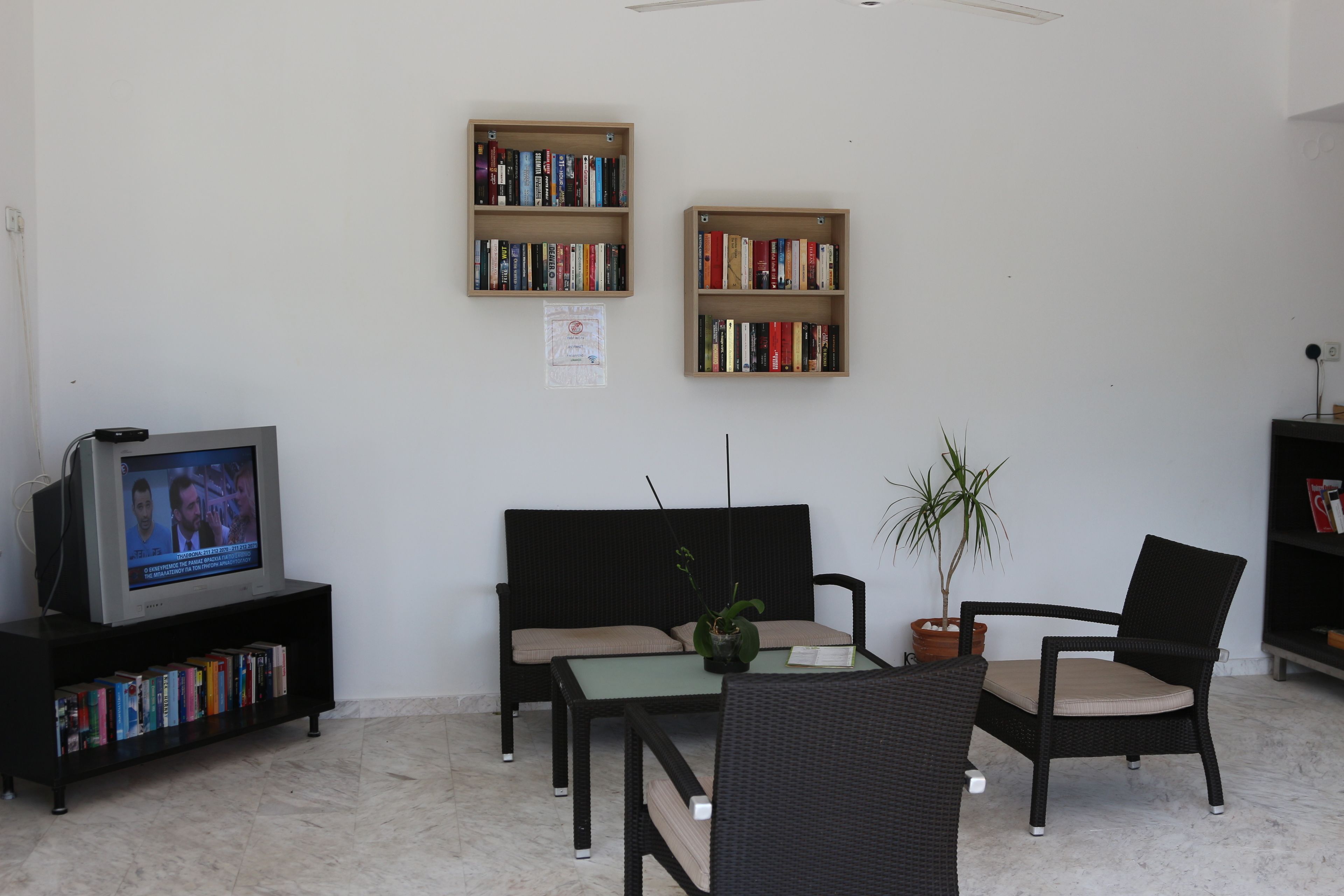 A living room with a sofa, two armchairs, a coffee table, a bookshelf, and a television.
