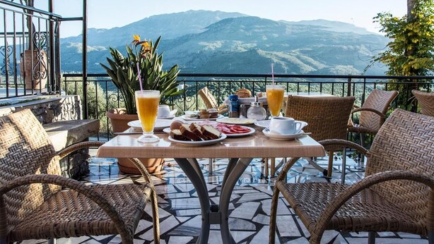 A table set with breakfast items, including toast, eggs, and juice, overlooking a mountainous landscape. - Alkion (Apokoronas)