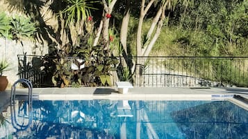 Una piscina al aire libre de temporada, sombrillas