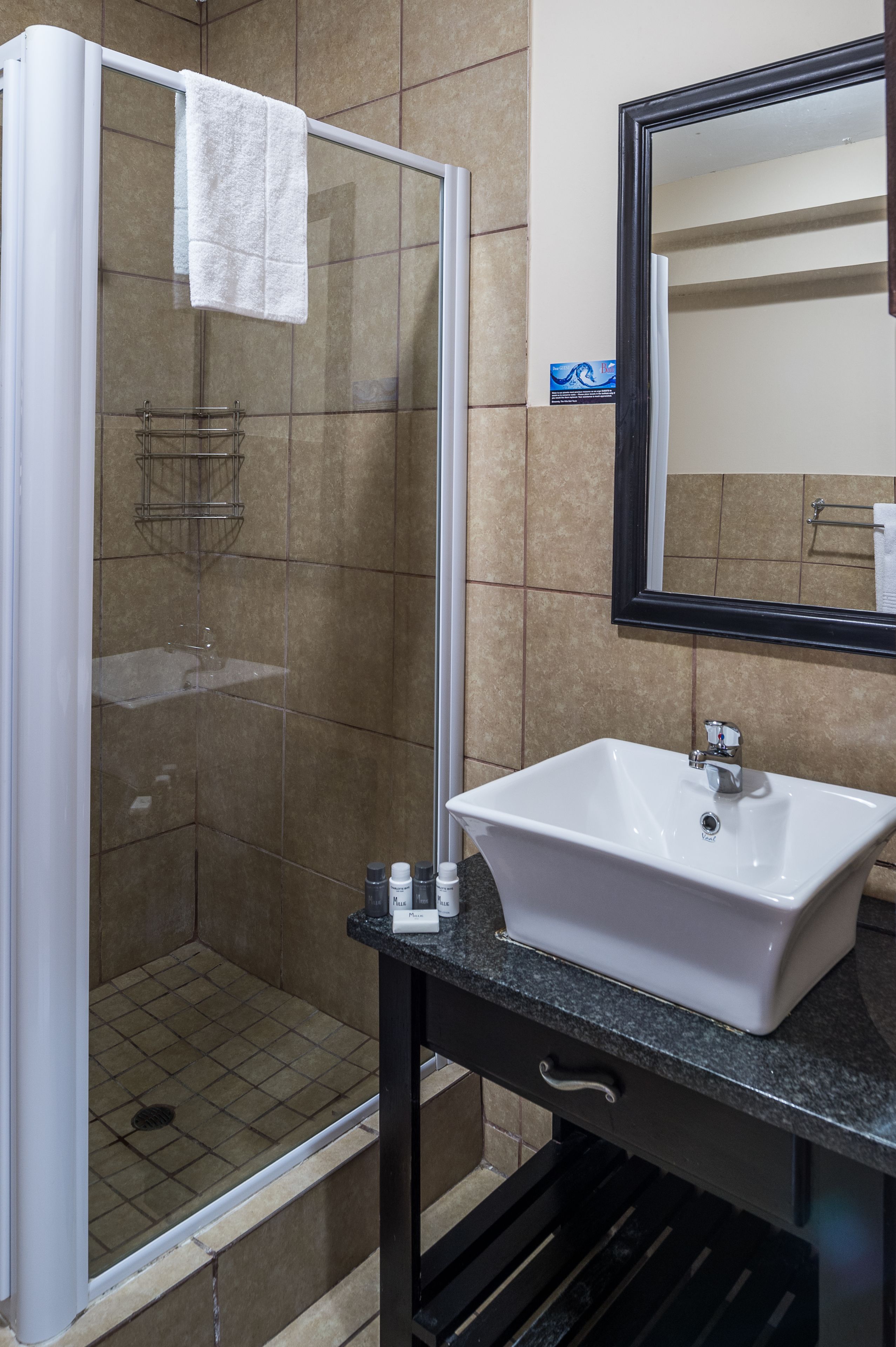A bathroom with a glass shower enclosure, a white sink, and a mirror.