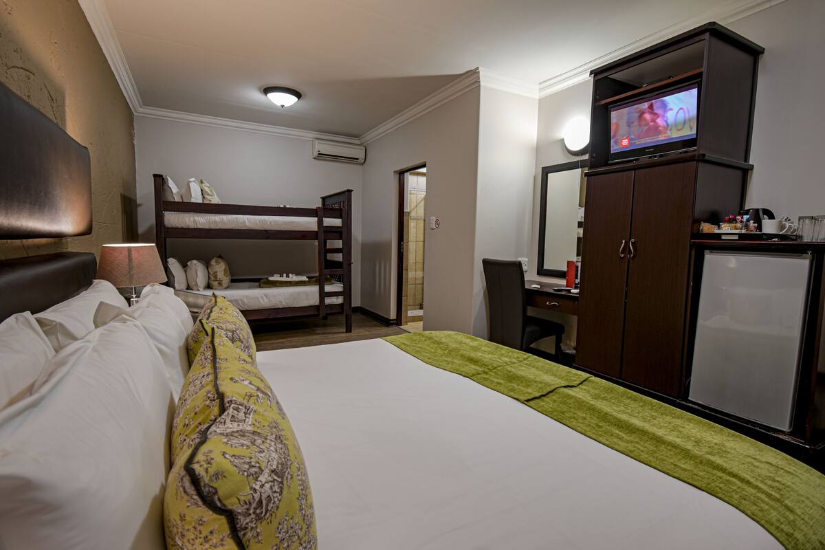 Una habitación de hotel con literas, un escritorio con ordenador, televisión y minibar.