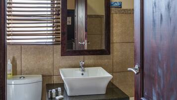 A bathroom with a toilet, sink, vanity, and a mirror.