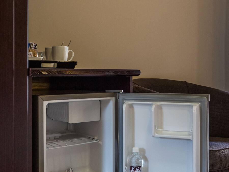 A small, dark wooden cabinet with a microwave on top.