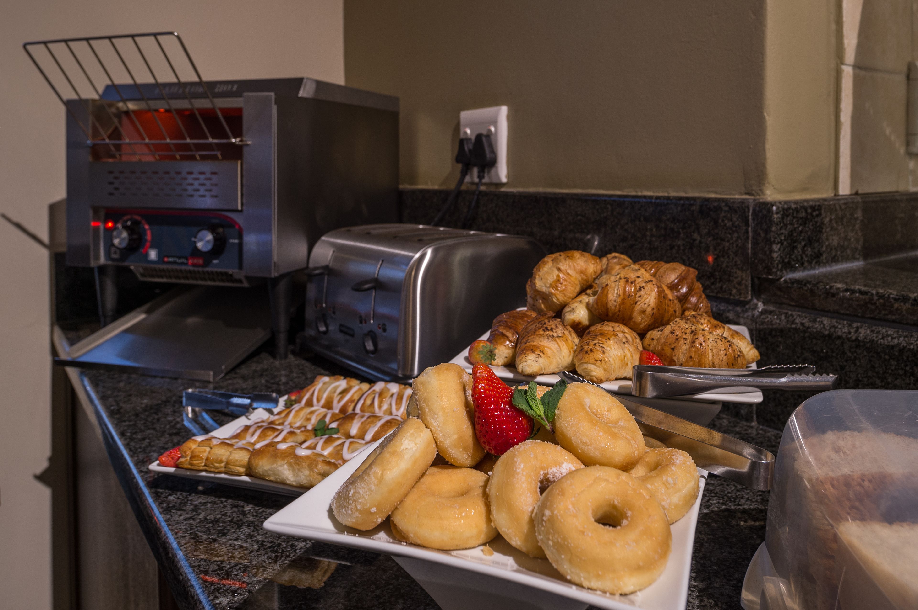 Un bufé de desayuno con diversos pasteles y un tostador.