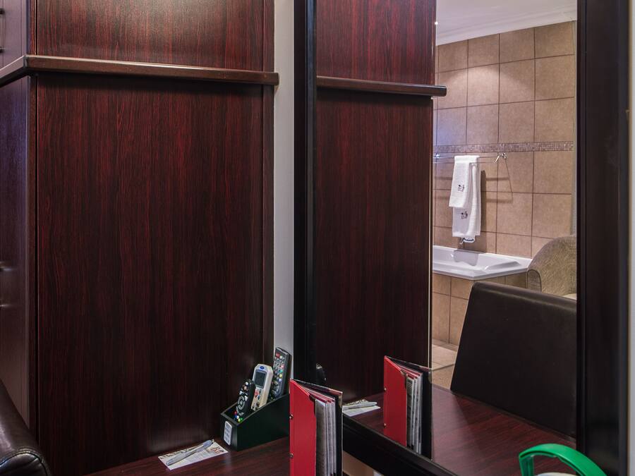 Une chambre d’hôtel avec un bureau en bois, un miroir, un téléphone et une lampe.