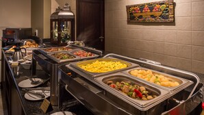 Un buffet proposant une variété de plats, notamment des œufs brouillés, des saucisses et des légumes.