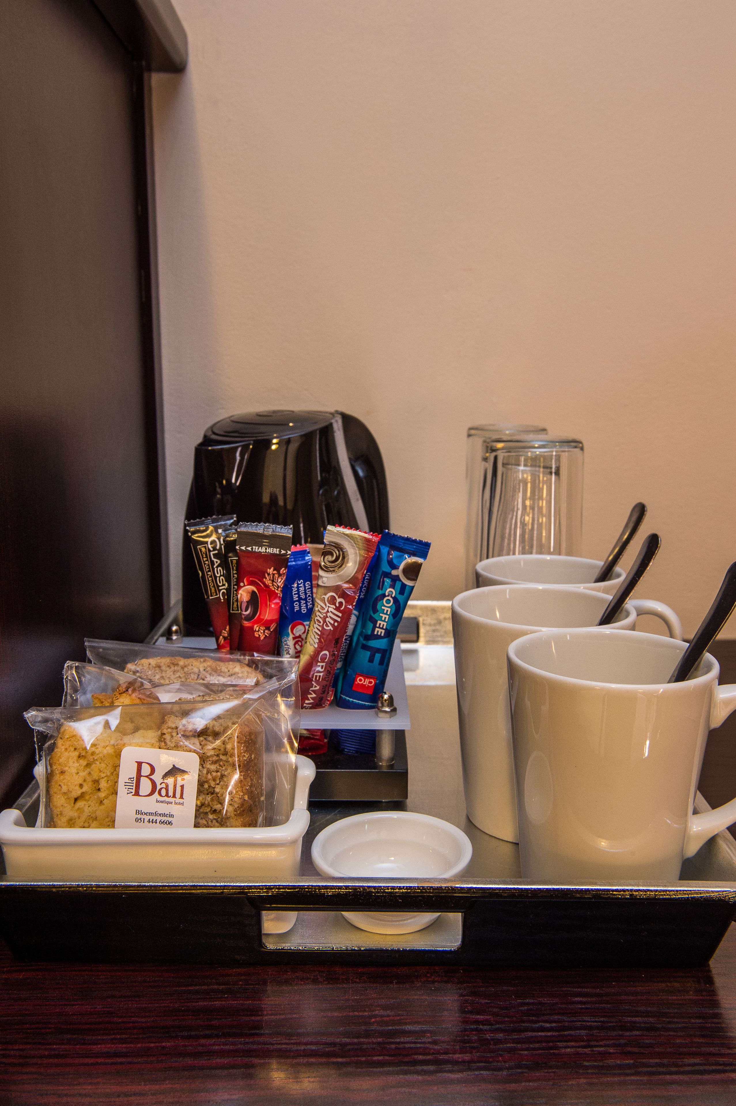 Un plateau avec des tasses à café, une machine à café et des en-cas emballés.