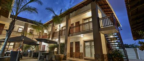 A multi-story hotel with outdoor seating, a staircase, and a well-maintained garden.