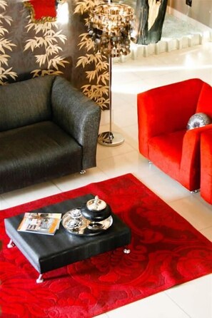 A living room with a black sofa, a red armchair, and a red patterned rug.